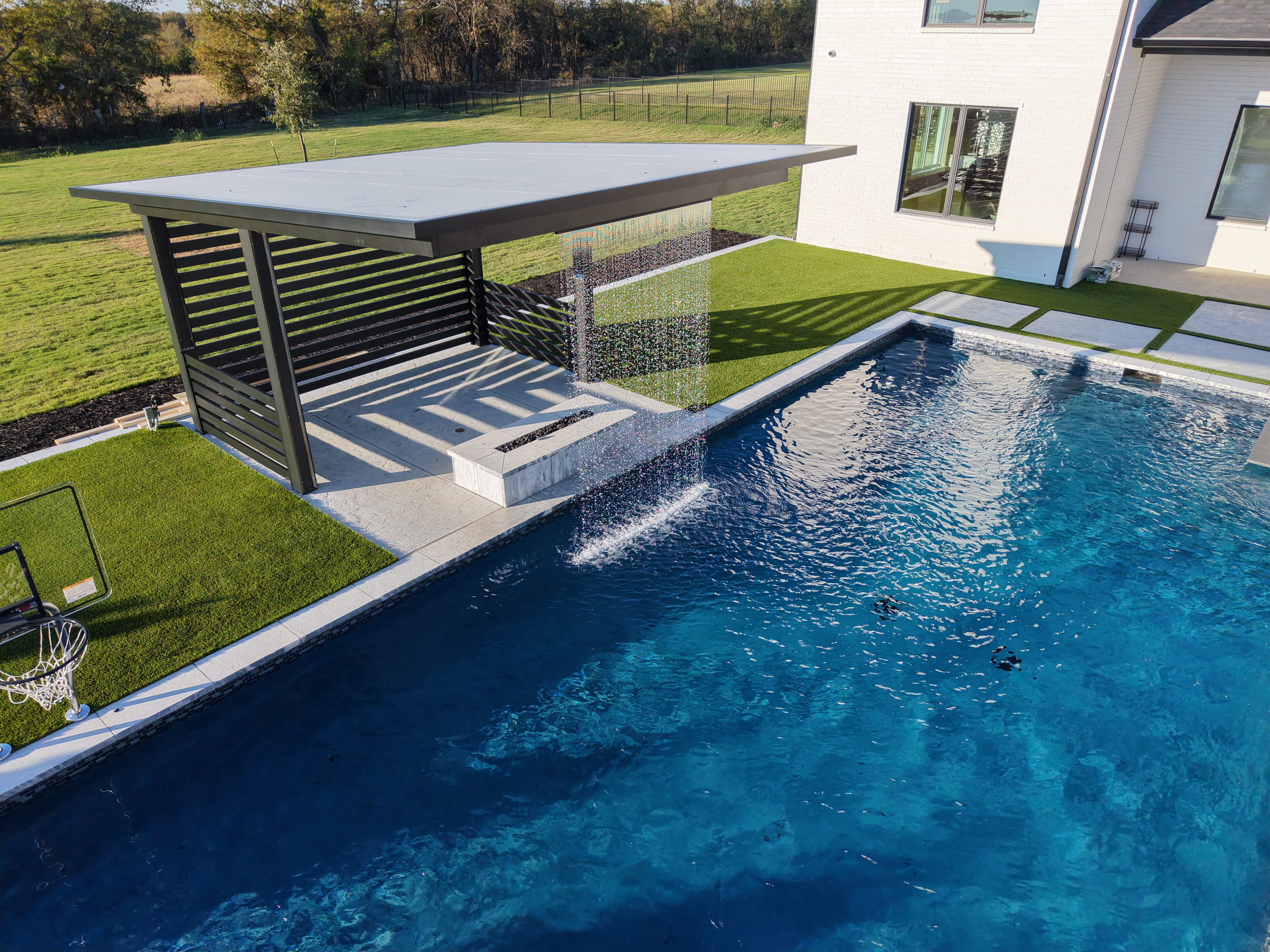 Luxury pool with rain wall water feature and natural stone hardscape