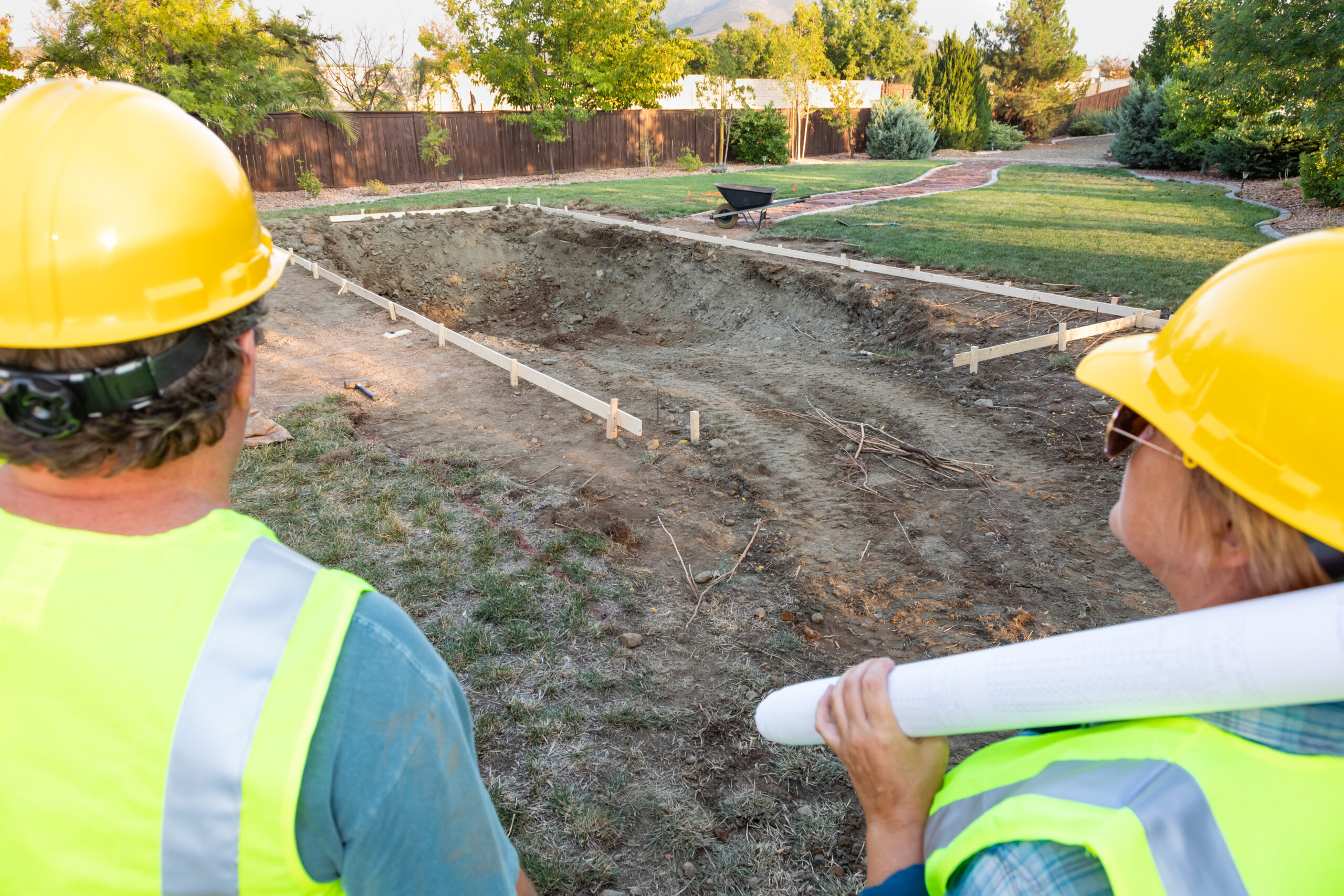 Male and Female Workers Overlooking Pool Construction Site